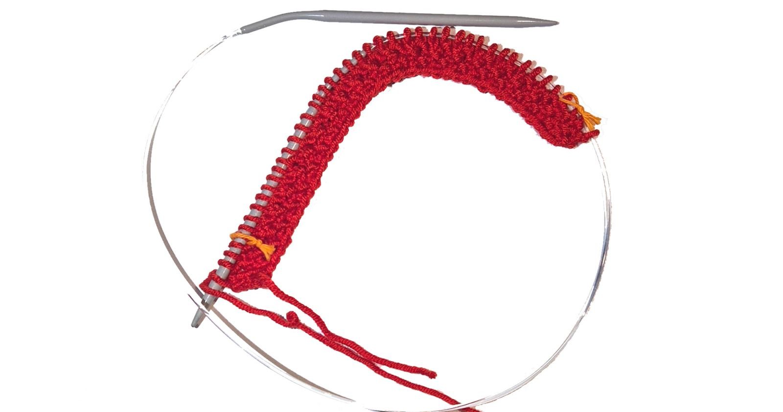 Eine Rundstricknadel mit einem roten Strickstück und 2 Maschenmarkierern aus Baumwollfäden.