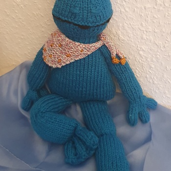 Die „richtige“ Wolle ist nicht mehr erhältlich. Mein Frosch ist mit dünnerer Wolle gestrickt. Die Hände habe ich verändert.